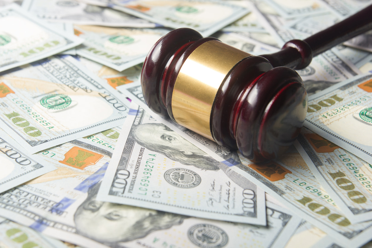 a gavel sitting on a floor covered in hundred dollar bills