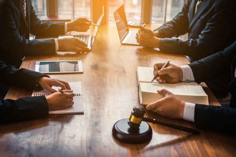 Attorneys discussing business law around a wooden table with a gavel
