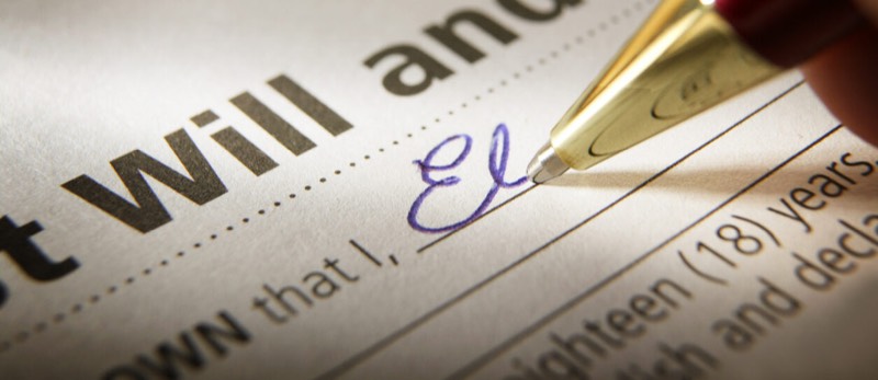 Man signing his estate planning documents that read "Last will and testimony"