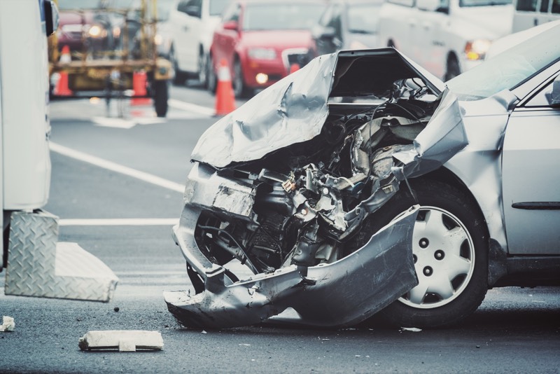 Car's hood destroyed in head on collision in the middle of the road causing personal injury